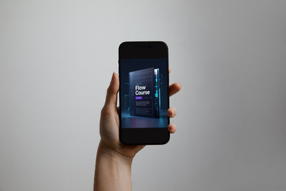A hand holding a black smartphone against a plain light gray background. The phone screen displays a digital course cover with the text 'Flow Course'.