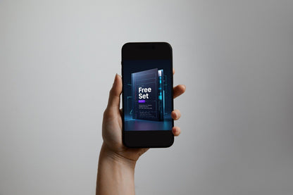A hand holding a black smartphone against a plain light gray background. The phone screen displays a promotional graphic with the text 'Free Set' and a dark server rack design.