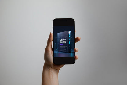 A hand holding a black smartphone against a plain light gray background. The phone screen displays a dark digital interface with the text 'Lattice Module'.